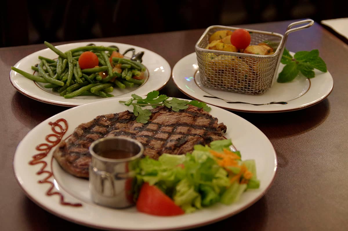 Entrecôte grillée accompagnée de haricots verts et de pommes de terre sautées.