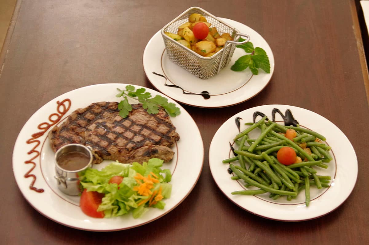 Entrecôte grillée marquée au gril, servie avec sa sauce, sa salade et ses garnitures.
