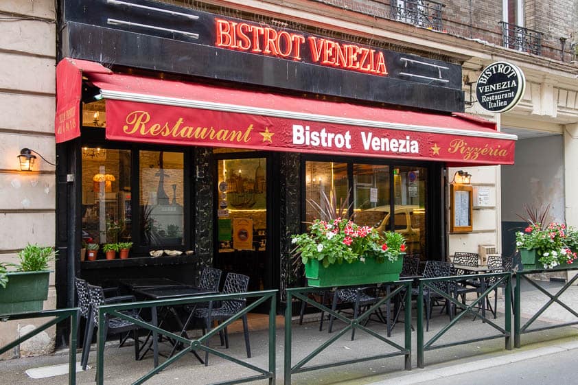 La façade du Bistrot Venezia, rue Godefroy à Puteaux, avec son store rouge et sa terrasse.