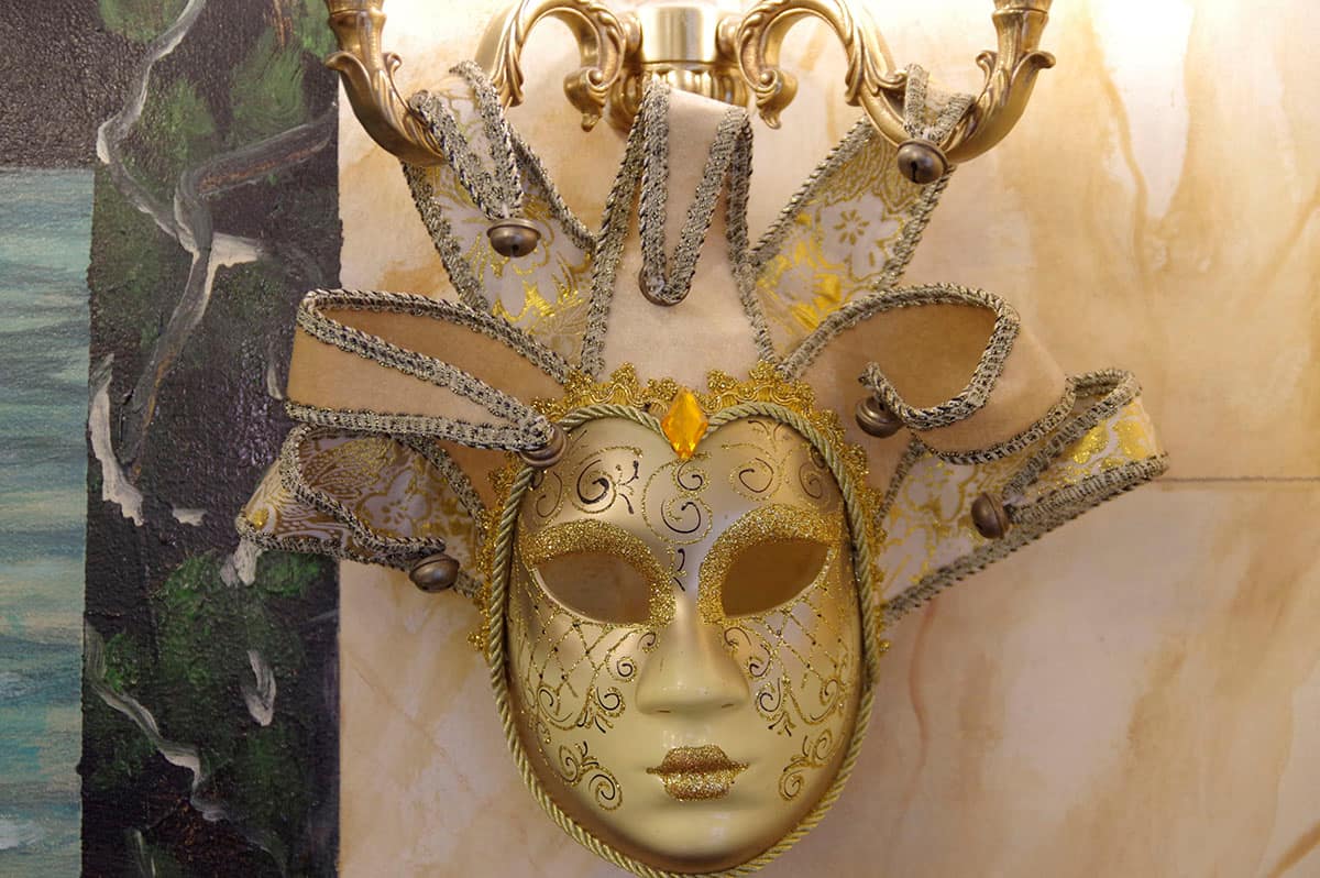 Masque vénitien doré sous une applique en laiton, dans la salle du restaurant.
