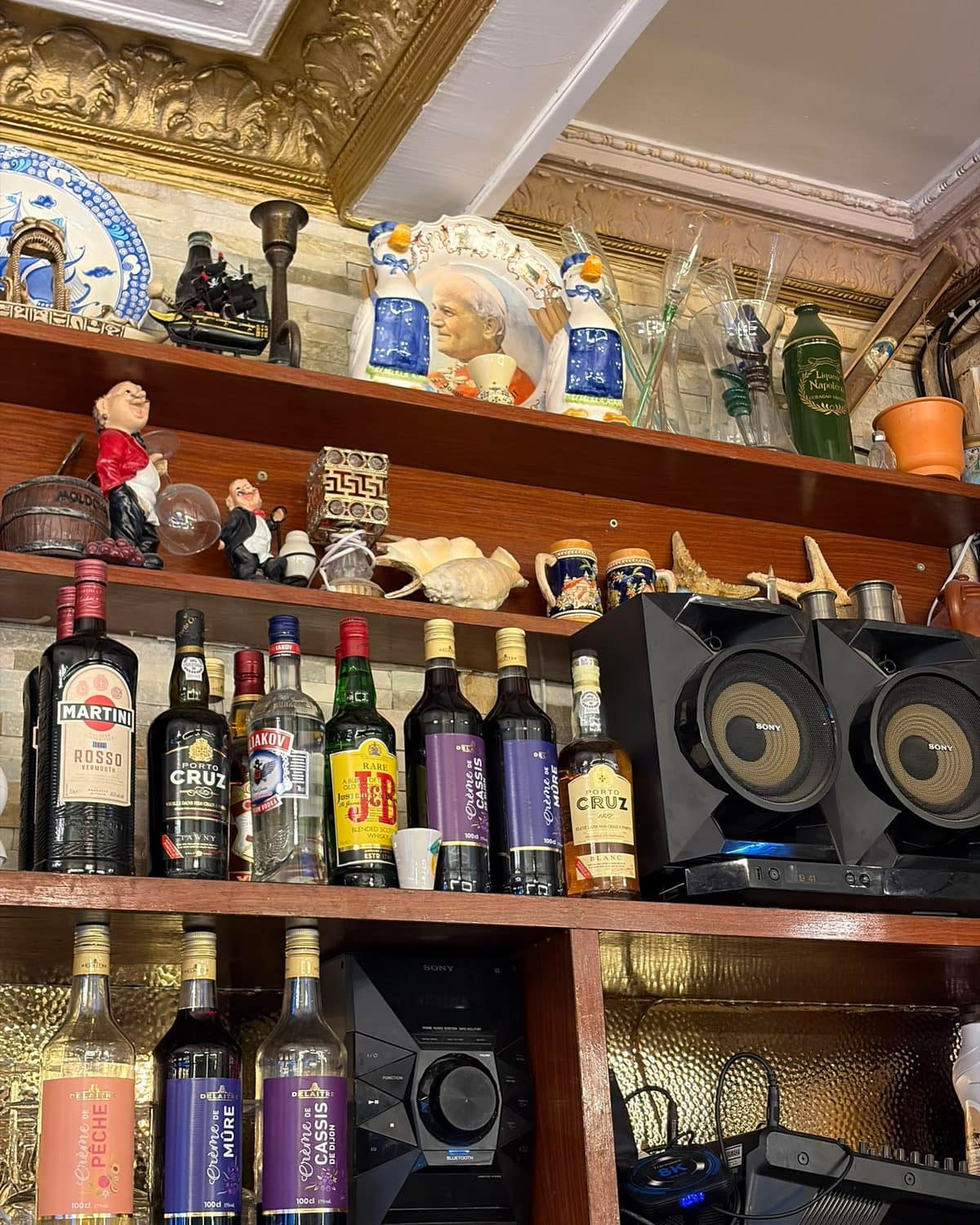 Les étagères du bar : bouteilles d’apéritifs et de digestifs, bibelots rapportés de Venise.