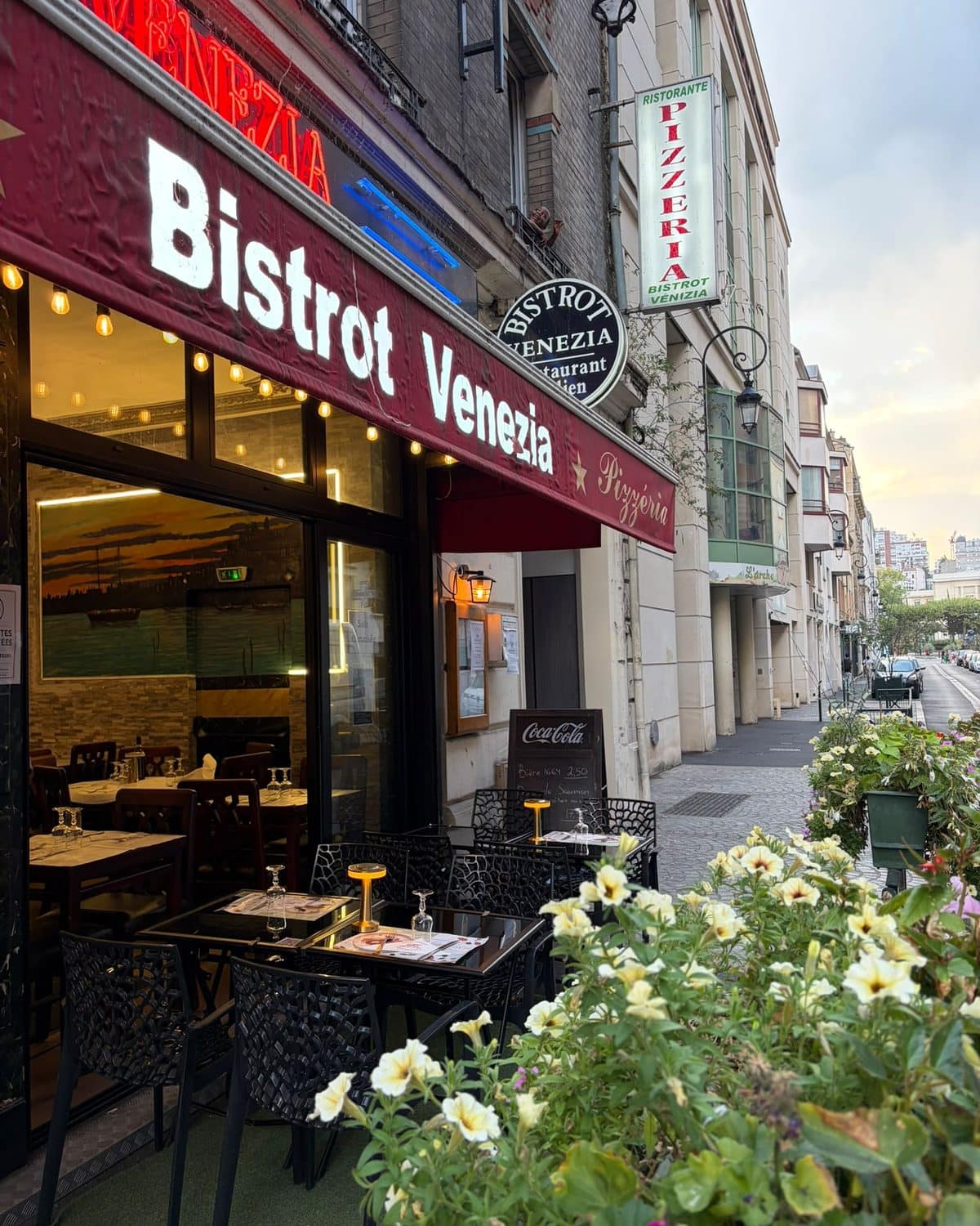 La devanture éclairée du Bistrot Venezia au crépuscule, la rue Godefroy en enfilade.