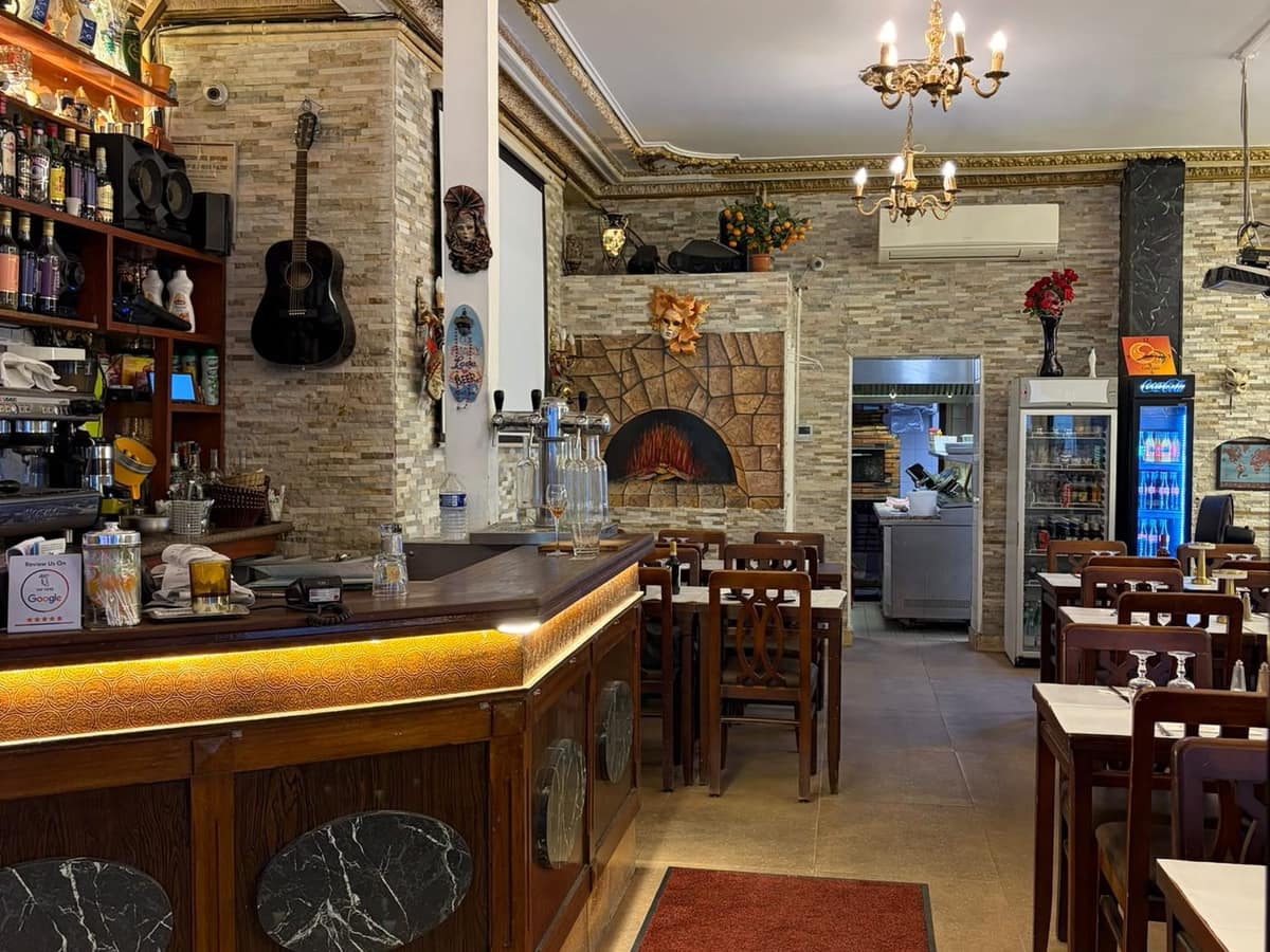 La salle du Bistrot Venezia en enfilade : comptoir, lustres et tables dressées de nappes blanches.